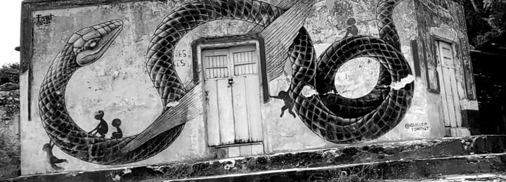 Mural on the front wall of a Mesoamerican building - a coiled winged serpent with five human figures on and around it. 