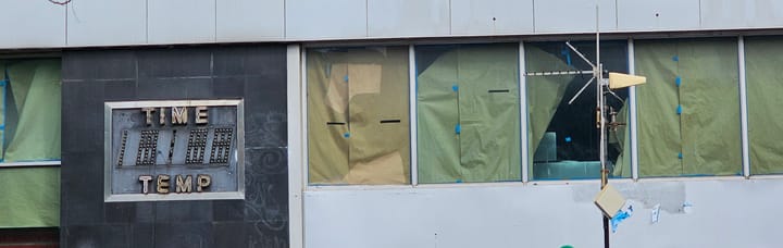 An NYC fossil: an old unused "time and temperature" sign beside empty office windows.